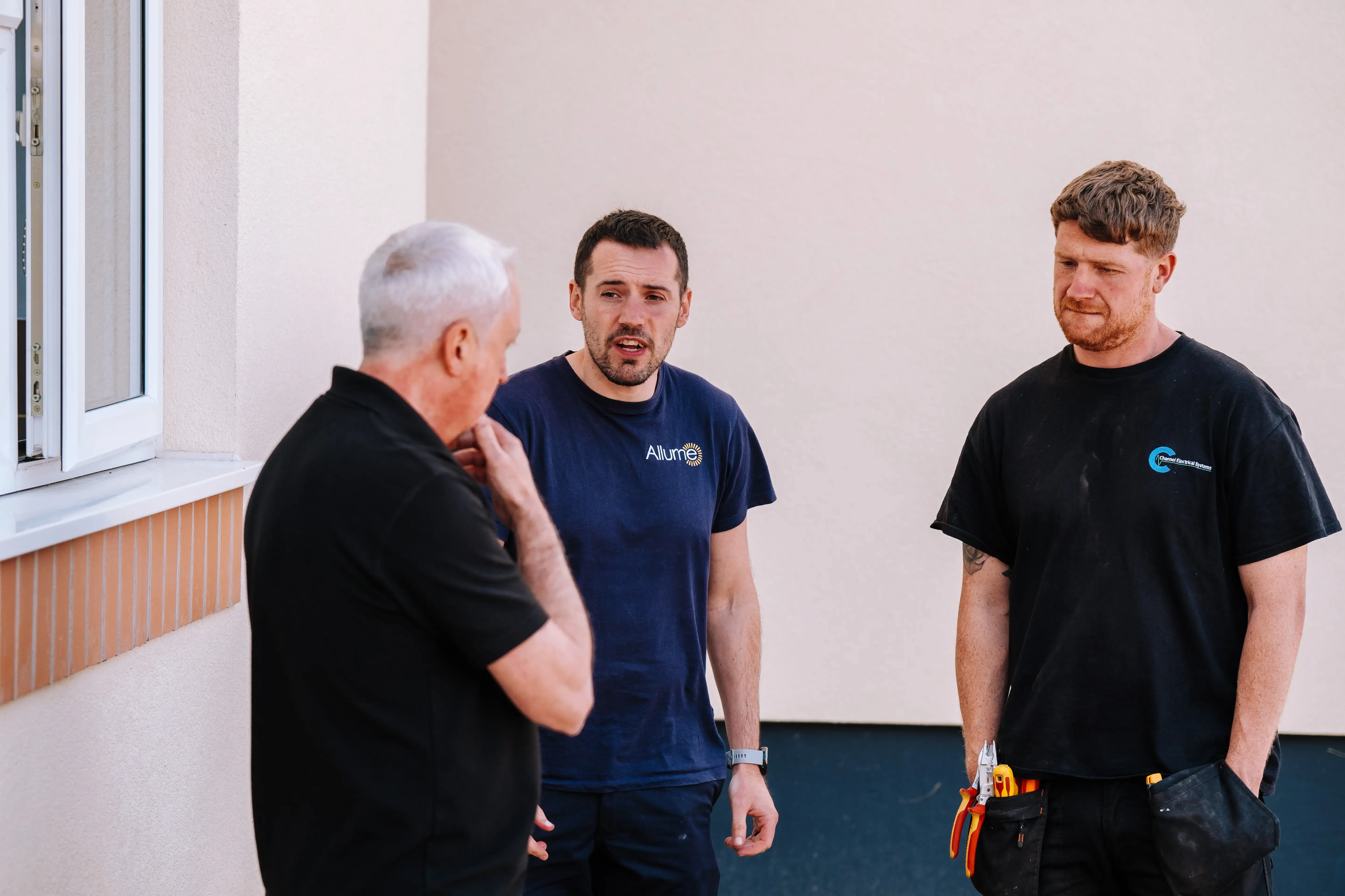 Allume team members engaging in a technical discussion about SolShare hardware with UK housing stakeholders and installers to plan a solar retrofit project for an apartment building.